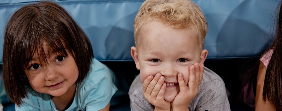 Zwei Kinder verstecken sich lachend unter der Weichbodenmatte