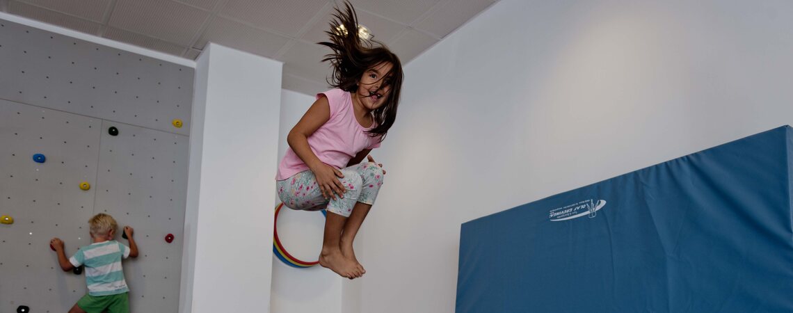 Mädchen springt vom Trampolin, Kind klettert an der Kletterwand