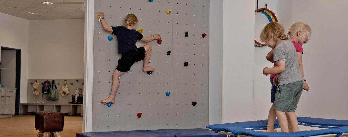 Kinder an der Kletterwand und auf dem Trampolin